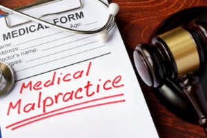 Medical form with words Medical Malpractice and gavel