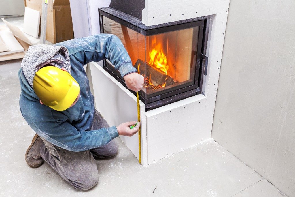 construction worker measuring fireplace