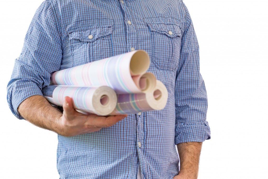 Man holding rolls of wallpaper