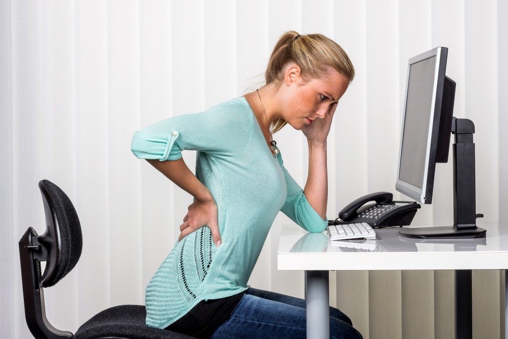 woman working, not feeling well because of back pain and headache