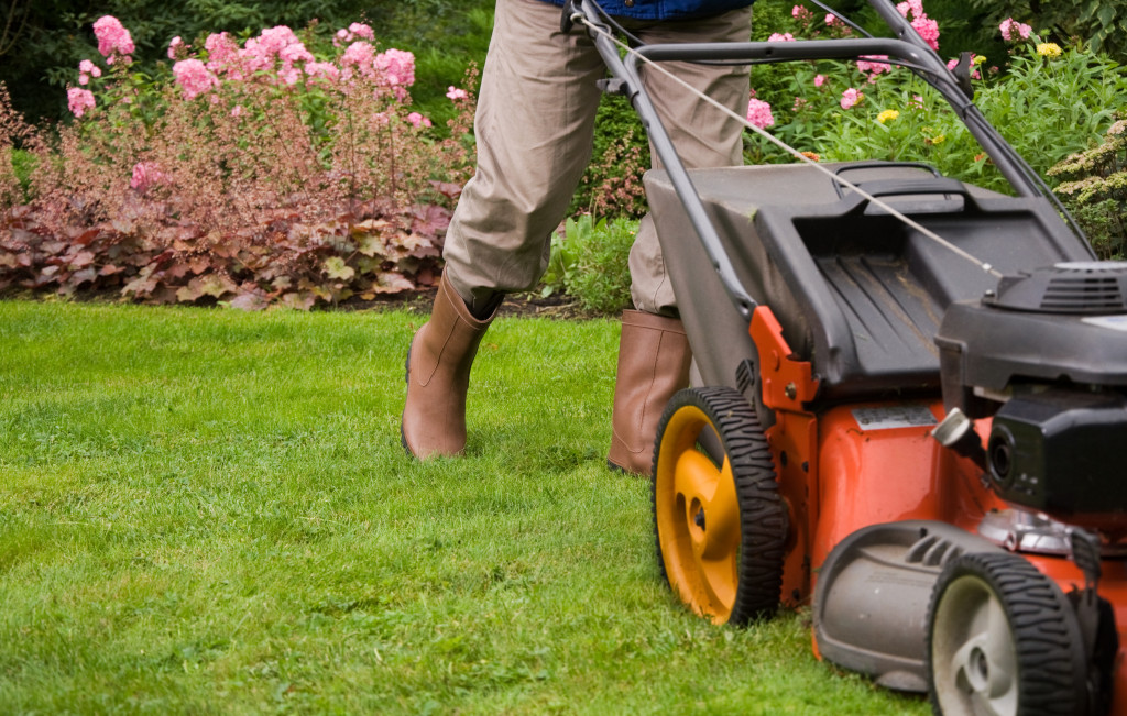 gardener using a lawnmower to cut grass