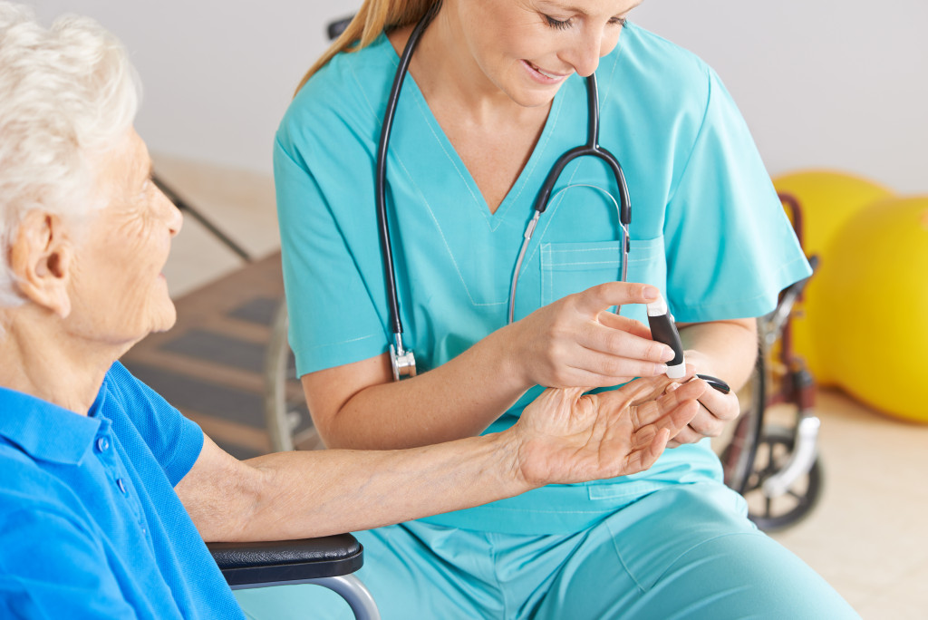 A geriatric nurse checks the blood sugar of a diabetic senior woman.