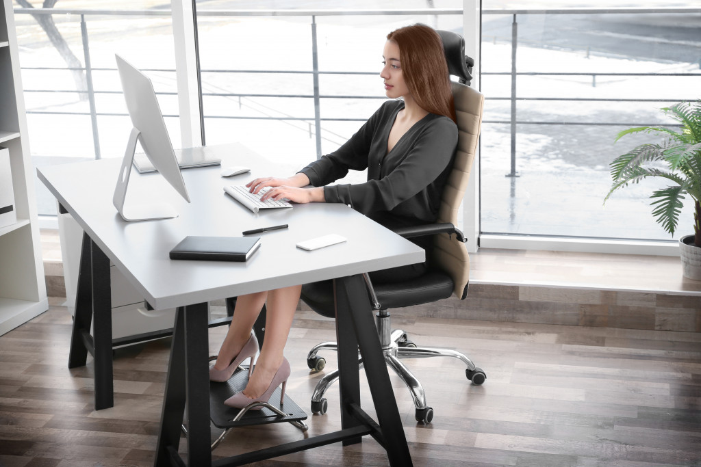 Young beautiful woman in office sitting with right posture working on computer