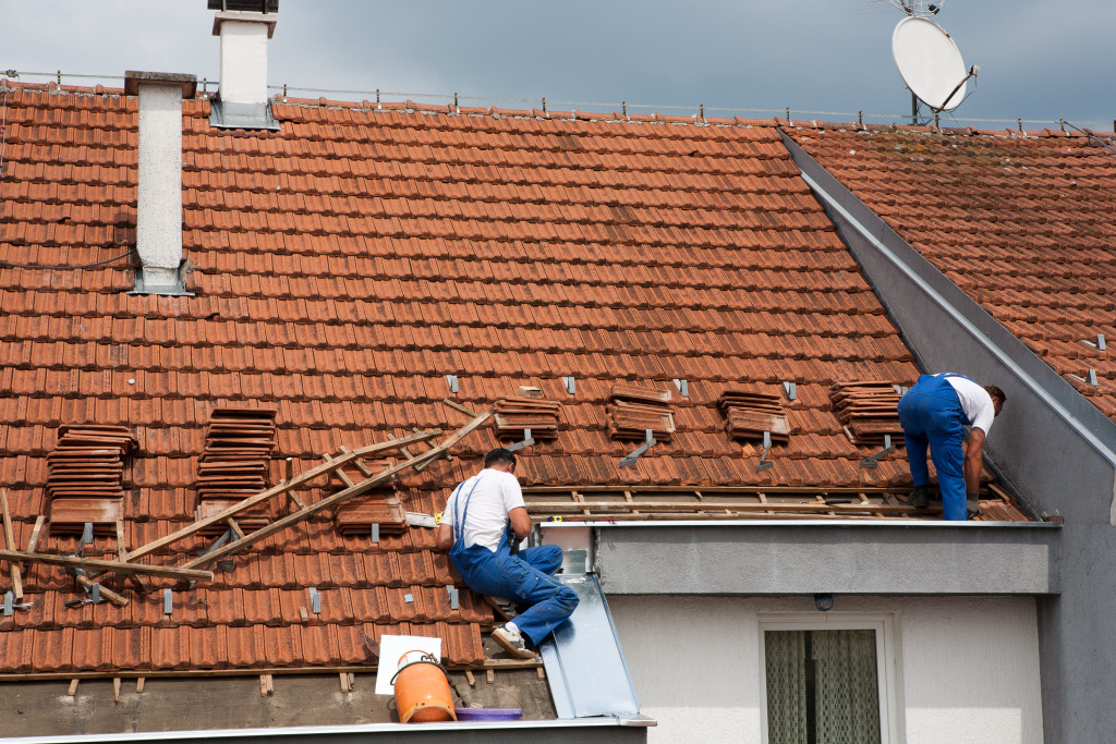 Two male roofers on top of the roof.