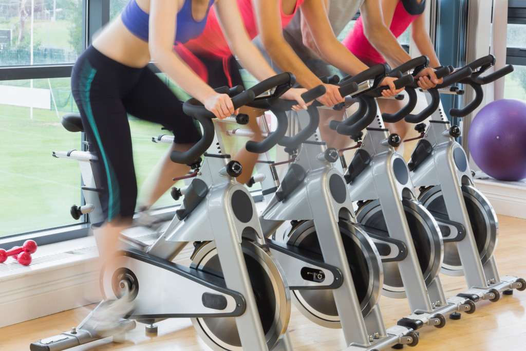 Young women using stationary bikes in a gym.