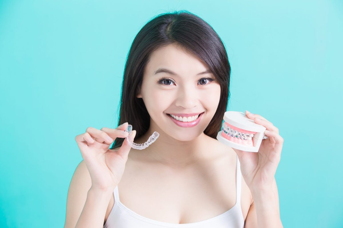 woman holding invisible braces and dental model